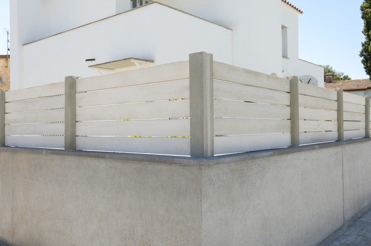 Valla imitación madera con vivienda al fondo